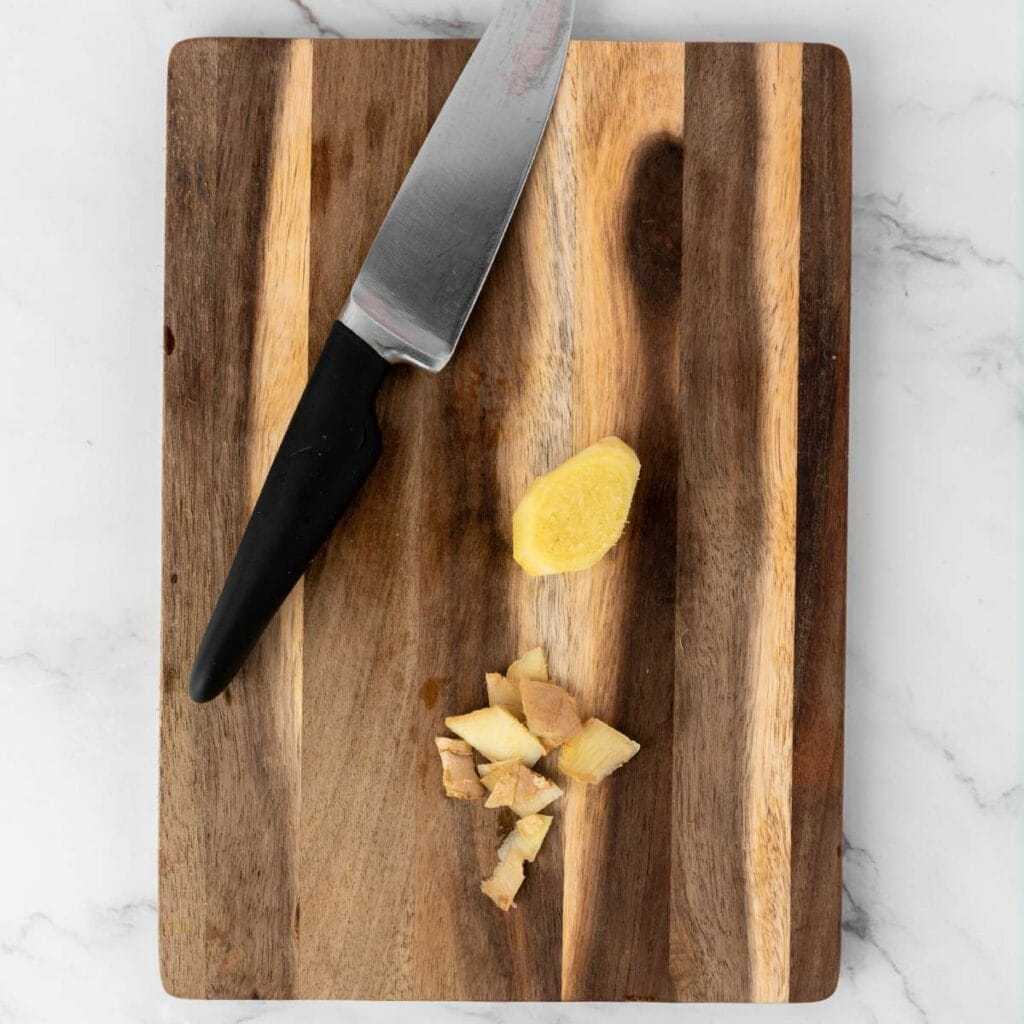 A kitchen knife and chopped ginger pieces.
