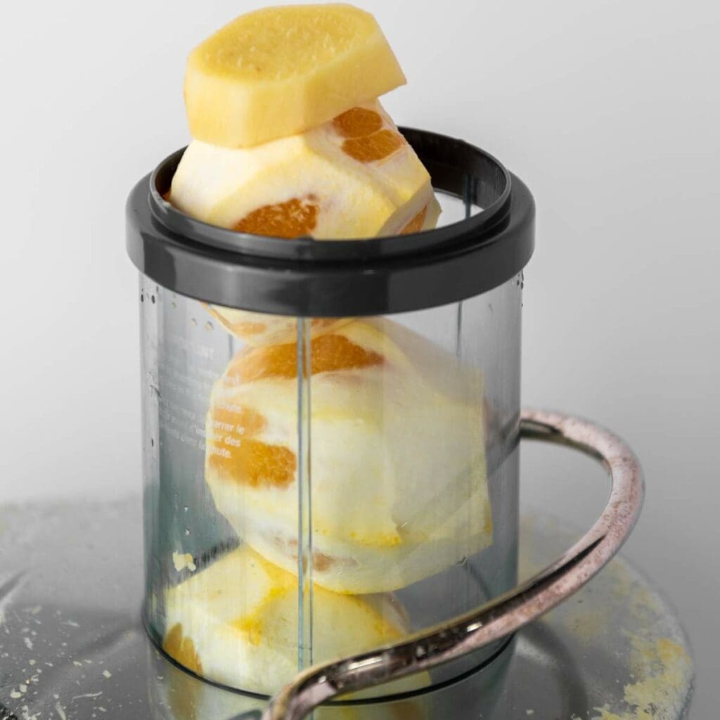 Peeled ginger pieces stacked inside a clear container.