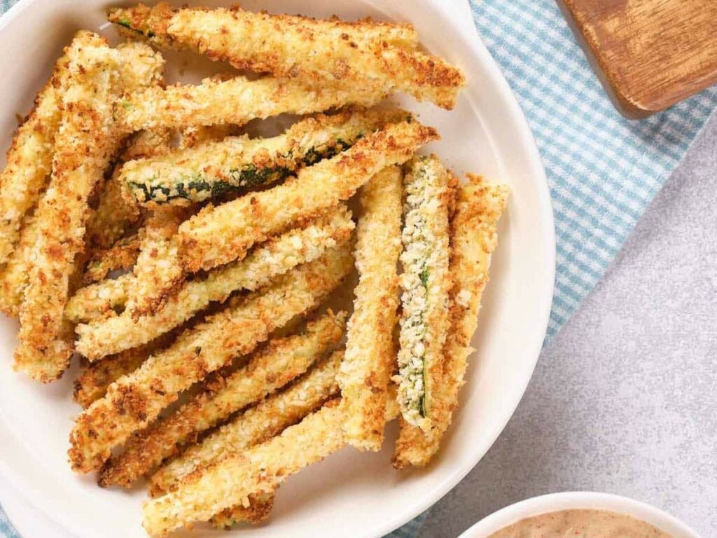 Plate of crispy, breaded zucchini fries on a white dish.