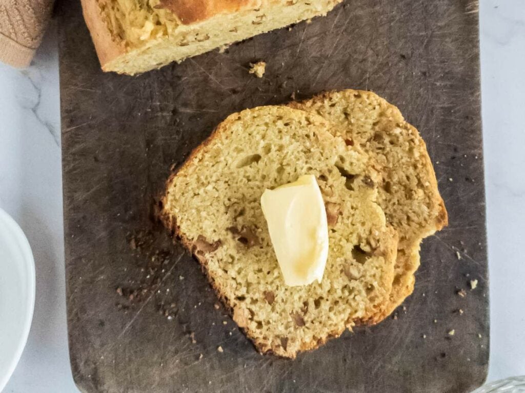 A slice of banana bread with a dollop of butter on top.
