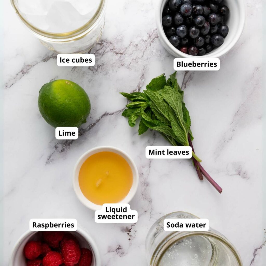 Assorted ingredients on a marble surface labeled of berry mocktail.