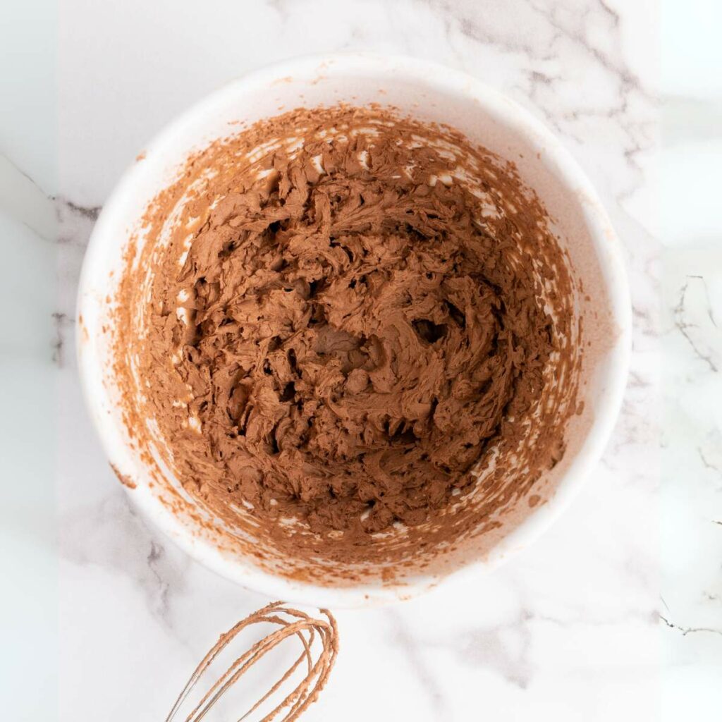 Two glasses of chocolate pudding with whipped cream.