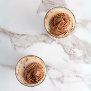 Two glasses of chocolate milk with whipped cream.