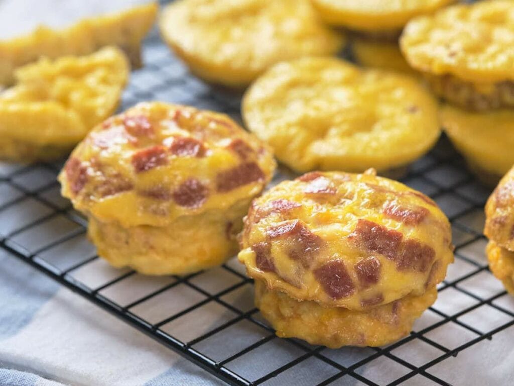 A close-up of double-stacked muffins shows off their crispy ham tops and fluffy, cheesy texture.