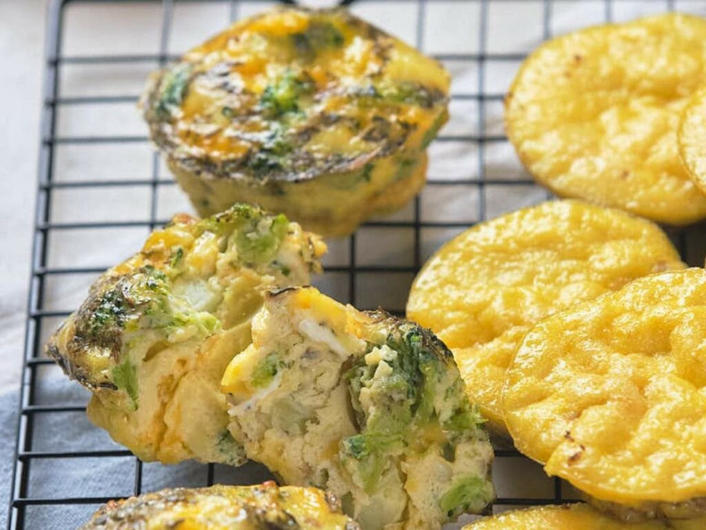 Broccoli and cheese muffins are sliced open to reveal a tender, veggie-filled interior.