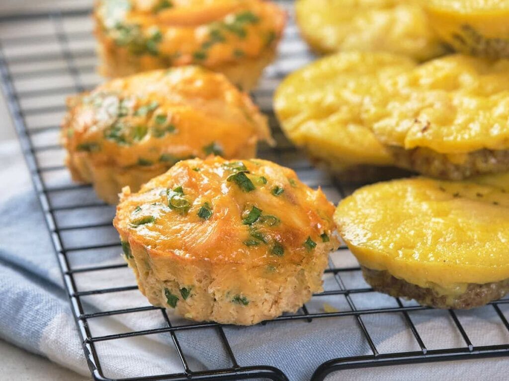 These egg muffins are loaded with chopped green onions, are cooling on a black wire rack.