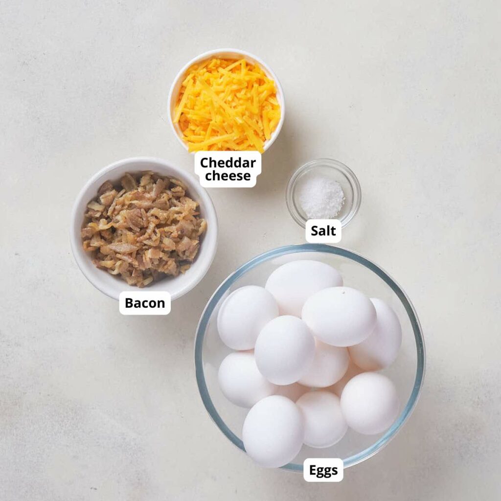 Ingredients for bacon cheddar egg bites, all labeled are arranged on a white surface.