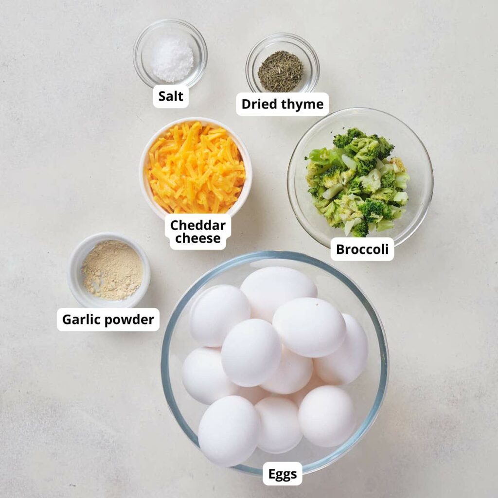 Ingredients for broccoli cheddar egg bites, all labeled are arranged on a white surface.