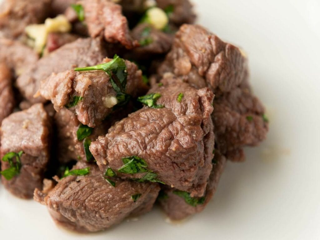 A tight shot of steak bites showcasing the texture of the meat and fresh herb garnish.