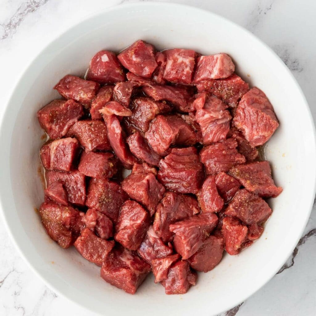 Steak pieces are coated with the seasonings and evenly marinated.