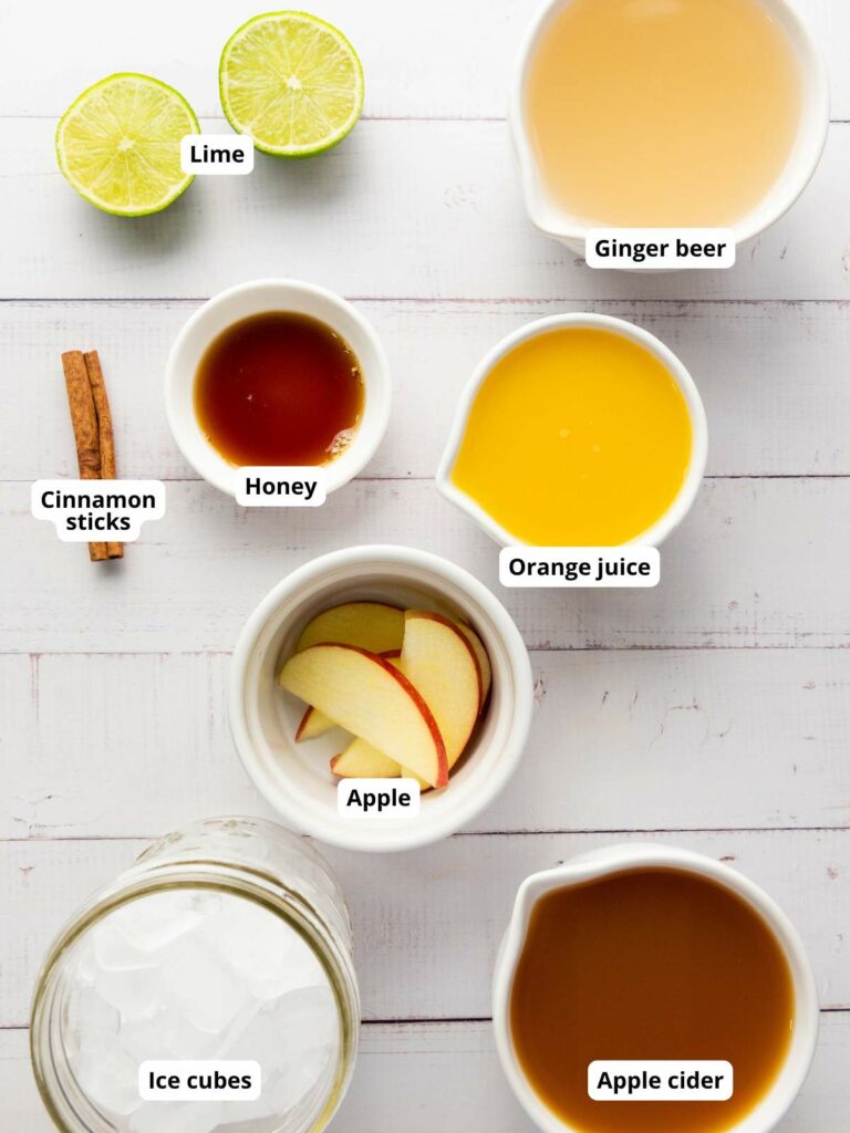 Top-down view of labeled ingredients on a white surface for ginger beer mocktail recipe.
