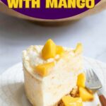 Slice of no-bake mango cheesecake topped with mango pieces on a white plate with a fork.