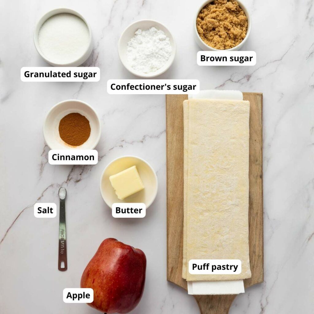 Ingredients for apple tart arranged on a marble surface.