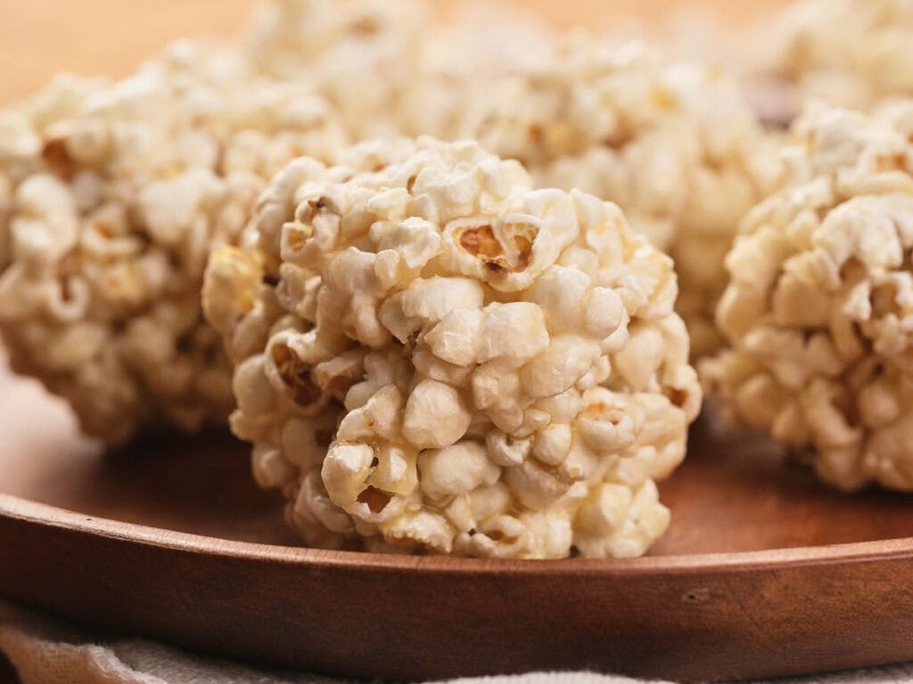 Close-up of several popcorn balls arranged on a wooden plate.