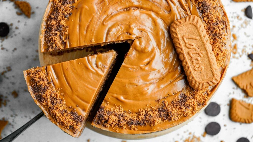 A top-down view of a Biscoff cheesecake with a slice being lifted out.