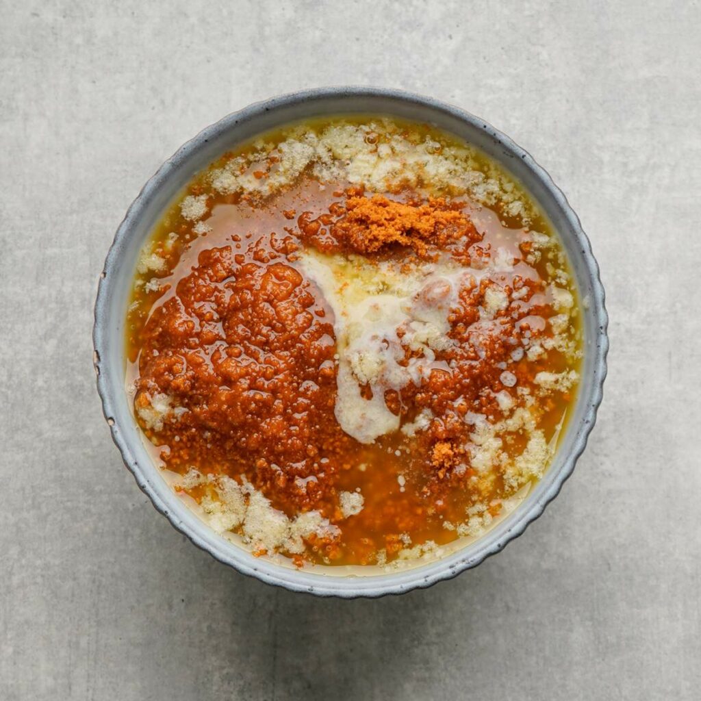 A bowl containing melted butter, brown sugar, and white sugar on a light gray surface.