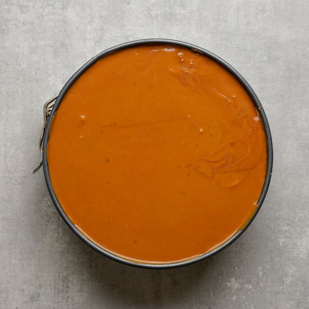 Round pan filled with smooth, orange-brown liquid mixture on a gray surface.