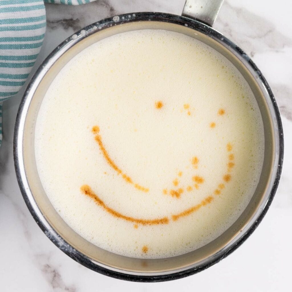 A metal saucepan filled with frothy milk.