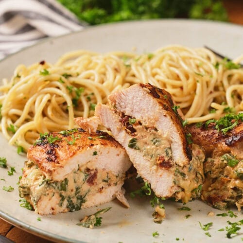 Sliced stuffed chicken breast with a creamy spinach filling, served alongside a portion of plain spaghetti on a plate.