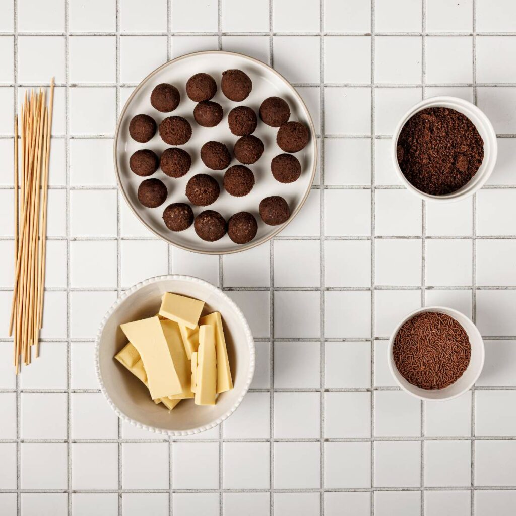 Spaghetti, chocolate balls on a plate, white chocolate pieces, and two bowls of chocolate sprinkles.
