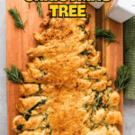 A puff pastry shaped like a Christmas tree, garnished with rosemary, displayed on a wooden board with salt and pepper shakers nearby.