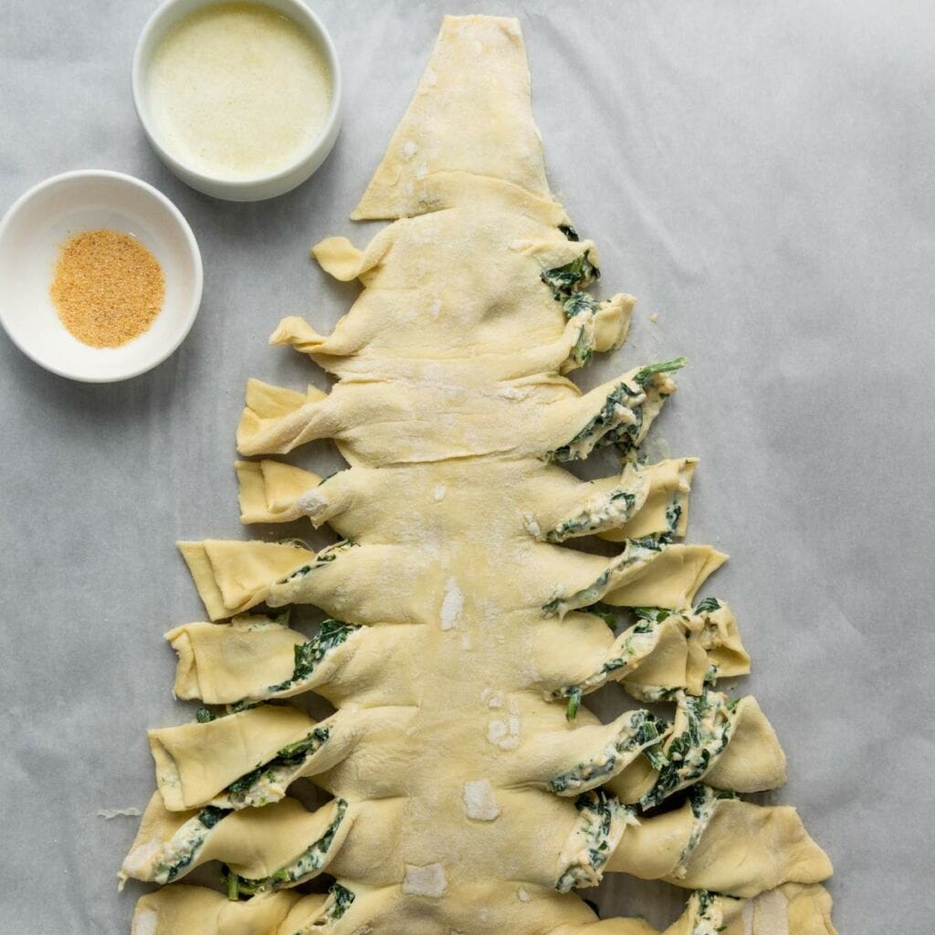 Unbaked puff pastry shaped like a Christmas tree, filled with spinach and cheese mixture.