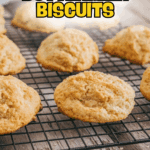 No-knead buttermilk biscuits cooling on a black wire rack with a wood surface underneath. Text overlay reads "No-Knead Buttermilk Biscuits.